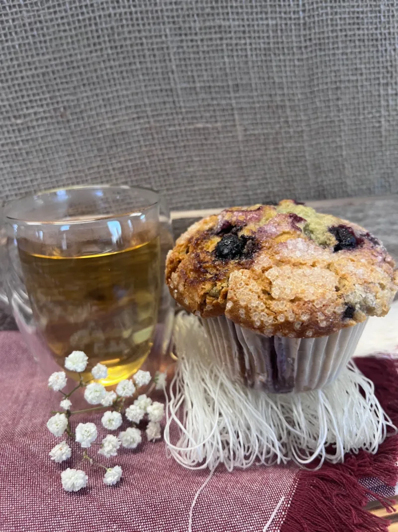 Blueberry muffin beside a glass of tea